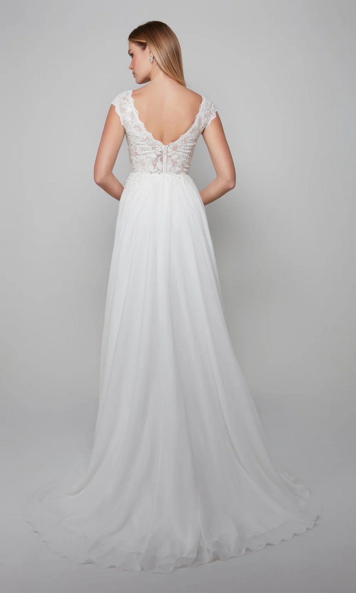 A woman faces away, wearing the Long White Dress: Alyce 7073 with lace-embroidered cap sleeves, a V-shaped back, and a flowing chiffon A-line skirt.
